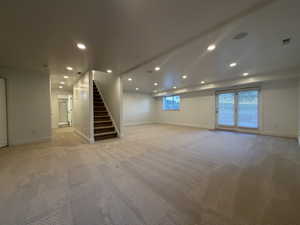 Basement with recessed lighting, light colored carpet, and stairs