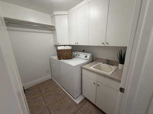 Washroom featuring light tile patterned floors, cabinet space, and washer and dryer