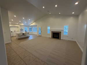 Great Room with recessed lighting, high vaulted ceiling, light tile-patterned floors, and a tile fireplace
