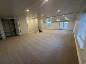 Basement featuring recessed lighting, light carpet, and stairs