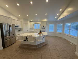 Kitchen featuring white appliances, a center island, recessed lighting, backsplash, and vaulted ceiling