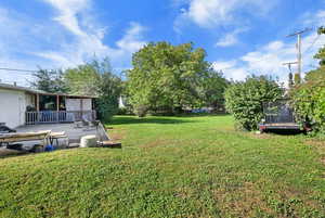 View of green lawn featuring a deck