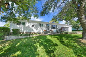 View of front of house featuring an attached garage, a front lawn, and a chimney