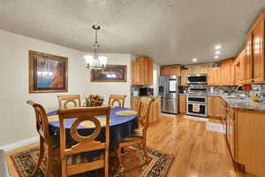 Dining space featuring a chandelier, light wood finished floors, a textured ceiling, and recessed lighting