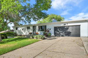 Single story home featuring brick siding, driveway, a chimney, a front yard, and a garage