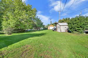 View of green lawn featuring a shed
