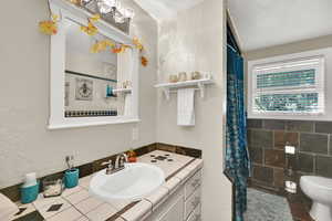 Full bathroom featuring a textured wall, vanity, tile patterned floors, a shower with shower curtain, and a textured ceiling