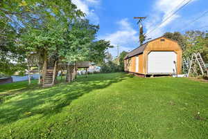 View of grassy yard featuring stairs, an outbuilding, and a wooden deck