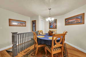 Dining area with light wood-style flooring, a textured ceiling, and a chandelier
