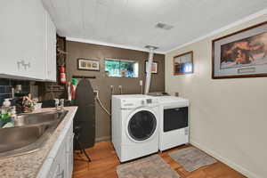 Washroom featuring light wood-style floors, washer and dryer, and ornamental molding