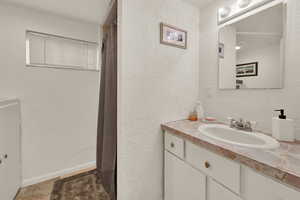 Full bathroom featuring a textured wall, vanity, and a shower with shower curtain