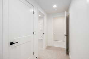 Hall with light colored carpet and recessed lighting
