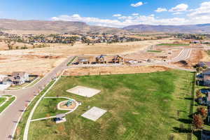 Aerial view of property and surrounding area featuring a mountainous background and nearby suburban area