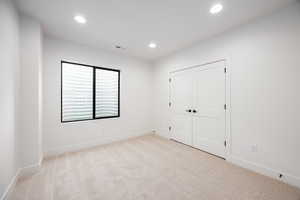 Unfurnished bedroom with light colored carpet, recessed lighting, and a closet