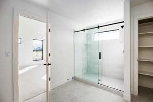 Bathroom with light colored carpet, light tile patterned floors, and a shower stall