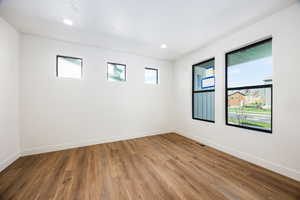 Empty room featuring plenty of natural light, wood finished floors, and recessed lighting