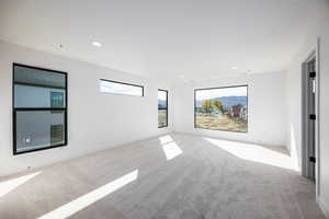 Empty room featuring light carpet, a mountain view, and recessed lighting