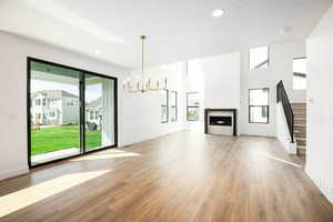 Unfurnished living room with a chandelier, light wood-style flooring, a fireplace, recessed lighting, and stairway