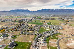 Aerial view of property and surrounding area featuring mountains and nearby suburban area