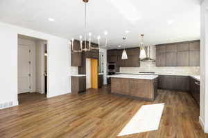 Kitchen featuring decorative backsplash, dark wood finished floors, a kitchen island, pendant lighting, and a chandelier