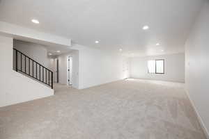 Spare room with light carpet, stairway, and recessed lighting