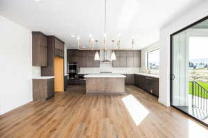 Kitchen featuring backsplash, a kitchen island, pendant lighting, modern cabinets, and light wood-style flooring