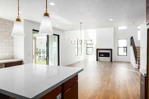 Kitchen with pendant lighting, open floor plan, a kitchen island, light wood finished floors, and light stone countertops