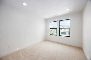 Spare room featuring light colored carpet and recessed lighting