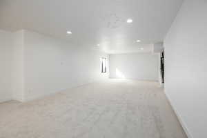 Empty room with light colored carpet and recessed lighting