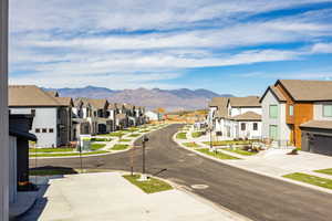 View of asphalt road with sidewalks, a mountain view, a residential view, and curbs