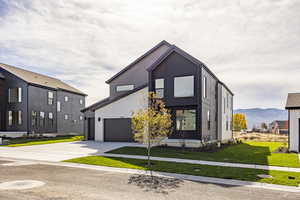 Contemporary house with a front yard, driveway, and a mountain view