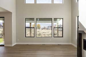 Unfurnished living room with light wood-type flooring, a high ceiling, and a fireplace