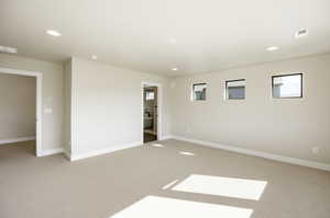Empty room with light colored carpet and recessed lighting