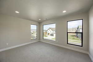 Spare room with light carpet, recessed lighting, and a residential view