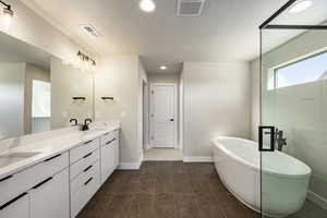 Full bathroom featuring a soaking tub, recessed lighting, and double vanity