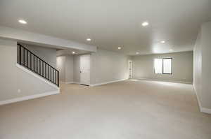 Spare room featuring stairs, light colored carpet, and recessed lighting