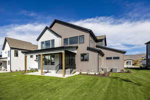 Back of property with a lawn, roof with shingles, a mountain view, and a porch