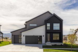 Modern home featuring concrete driveway, a front yard, and a mountain view
