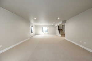 Empty room with stairs, recessed lighting, and light carpet