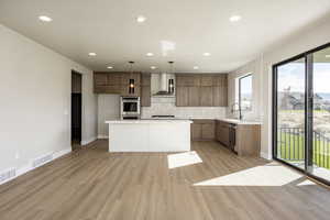 Kitchen with modern cabinets, light wood-style floors, a kitchen island, decorative backsplash, and recessed lighting