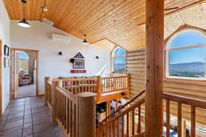 Hallway featuring wooden ceiling, vaulted ceiling, plenty of natural light, a mountain view, and an upstairs landing