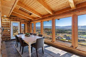 Dining room with a mountain view, wood ceiling, stone tile floors, and log walls