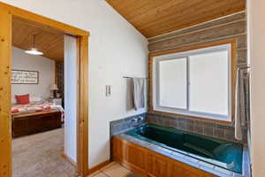 Ensuite bathroom with wooden ceiling, a garden tub, lofted ceiling, and light tile patterned flooring