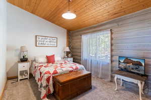 Bedroom featuring wooden ceiling, carpet flooring, log walls, and lofted ceiling