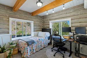 Bedroom featuring a desk, beamed ceiling, carpet, and log walls