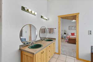 Ensuite bathroom featuring a textured wall, light tile patterned flooring, and double vanity