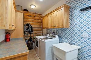 Laundry area with cabinet space, a textured ceiling, washer and dryer, and wallpapered walls