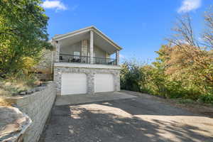 View of side of home with a balcony, asphalt driveway, and a 2 car garage