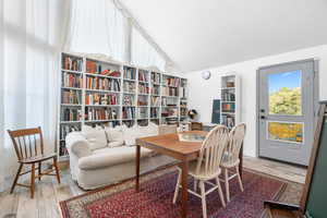 Library featuring vaulted ceiling, light wood-style tile floors, access to covered deck.