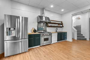 Kitchen #2 featuring a drop ceiling, stainless steel appliances, light wood finished floors, open shelves, and butcher block countertops
